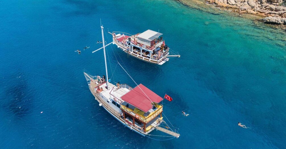Two boats anchored in clear blue water with rocky shorelines. 4