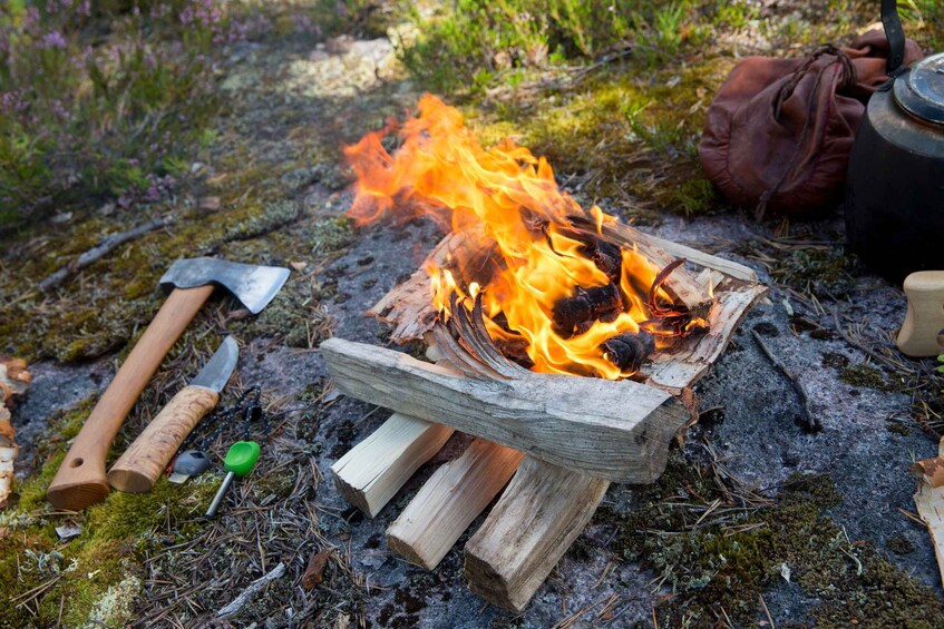 Nuotiolla on polttopuita, kattila ja retkeilyvälineitä maassa. 2