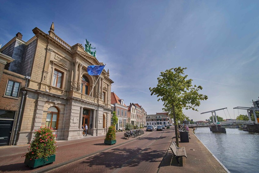 A canal with a bridge, a row of historic buildings, and a tree-lined sidewalk. 1
