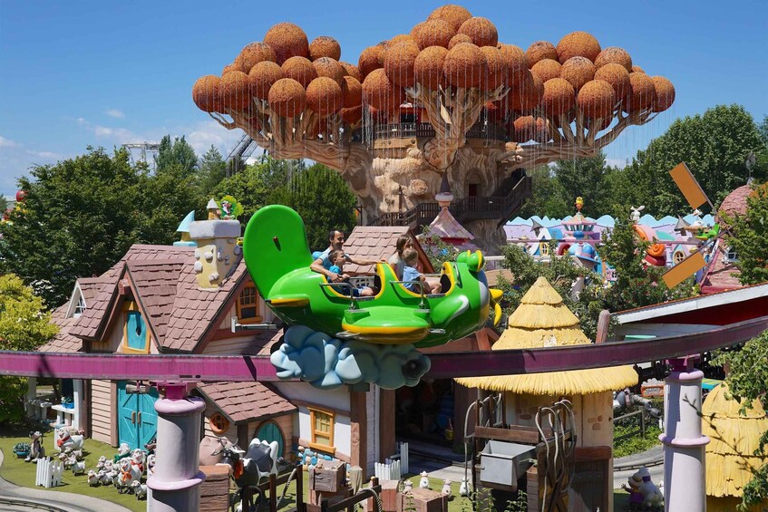 A green roller coaster with passengers, a treehouse with spherical structures, and a whimsical village with buildings and decorations. 3
