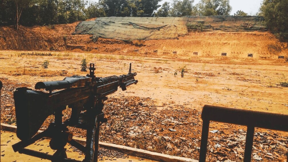 Un rifle sobre un banco con vistas a un paisaje árido y escaso, con vegetación dispersa y un risco rocoso. 5