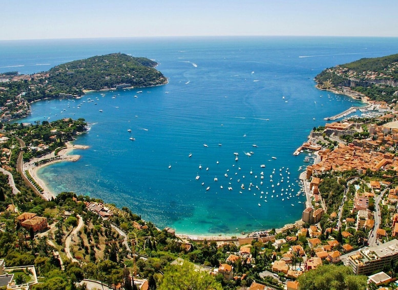 A coastal town with a bay filled with boats, surrounded by hills and red-roofed buildings. 5