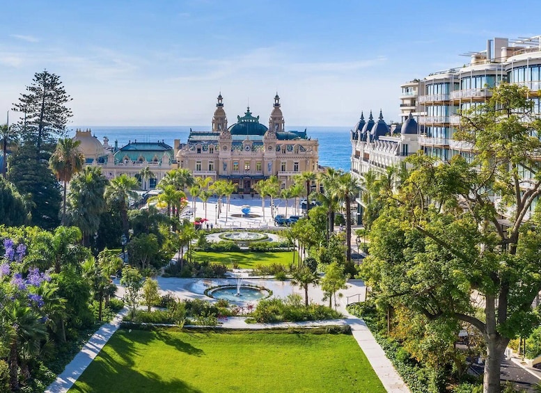 A grand building with domed roofs, a central fountain, and a clear view of the sea. 4