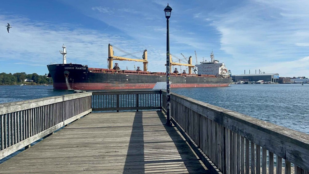 Une jetée en bois mène à un port où sont amarrés de grands navires de transport de marchandises. 2