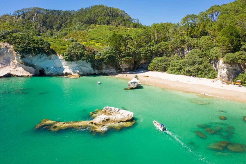 A coastal landscape with clear turquoise waters, rocky outcrops, and a sandy beach. 3