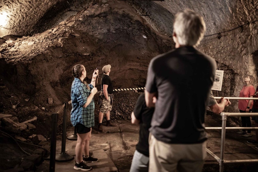 A group of people inside a cave with rocky walls and a sign on the right. 4