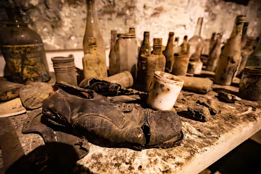 A cluttered table with old, worn-out shoes, jars, and bottles. 3