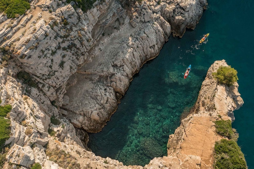 A rocky coastline with clear blue waters and kayaks. 5