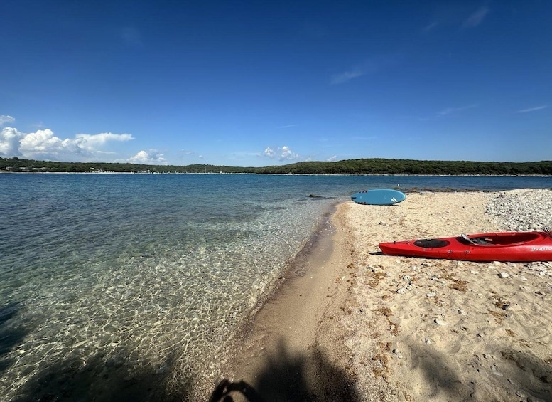A beach with kayaks, clear water, and a distant shoreline. 3