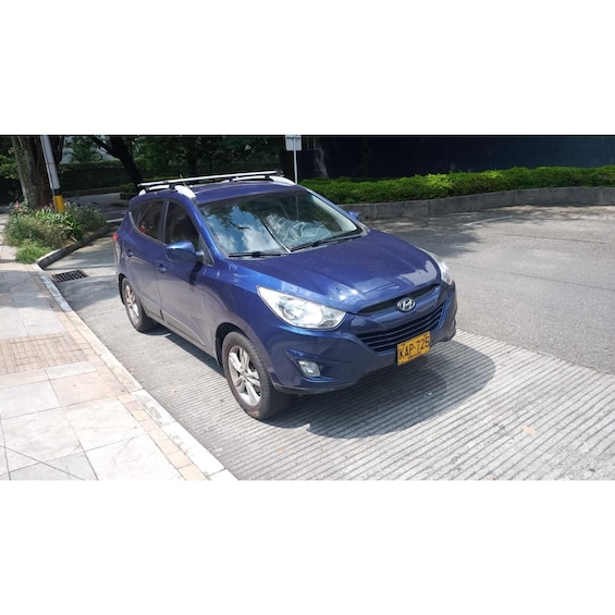 A blue Hyundai Tucson parked on a sidewalk with a yellow license plate. 4