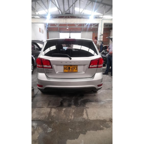 A silver car with a yellow license plate in a garage. 2