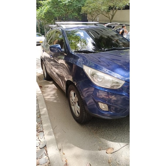 A blue SUV parked on a street with trees and a building in the background. 5