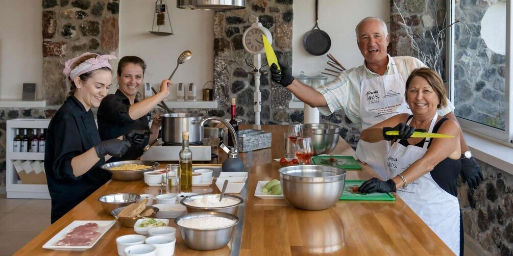 A group of people cooking in a kitchen with various ingredients and utensils on the counter. 1