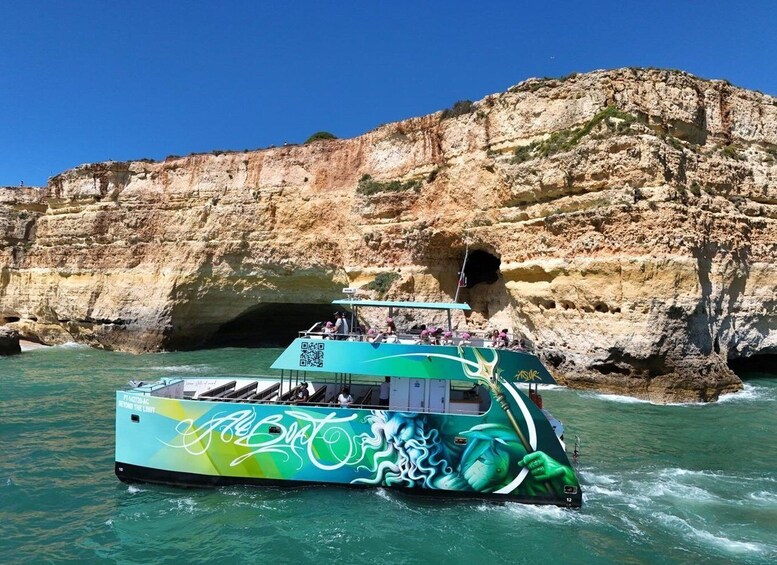 A boat with graffiti, sailing near a rocky cliff with a cave entrance. 5