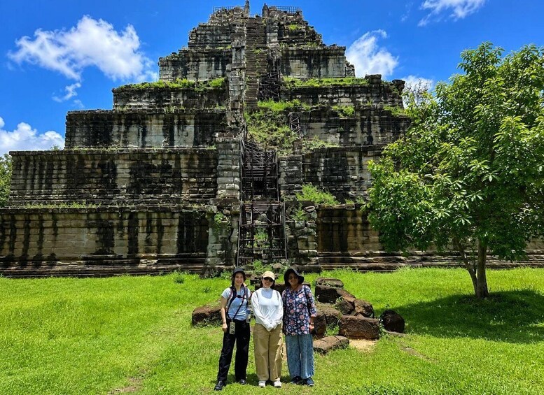 A large ancient stone structure with a central staircase, surrounded by lush green grass and a clear blue sky. 3