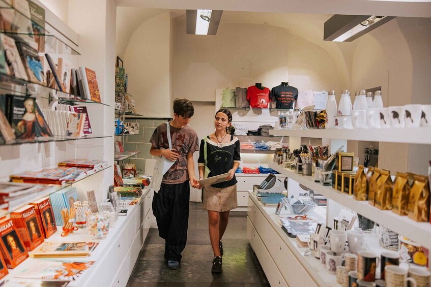 Una librería con estanterías llenas de libros y revistas, un mostrador con distintos artículos, y una persona sosteniendo un libro. 4