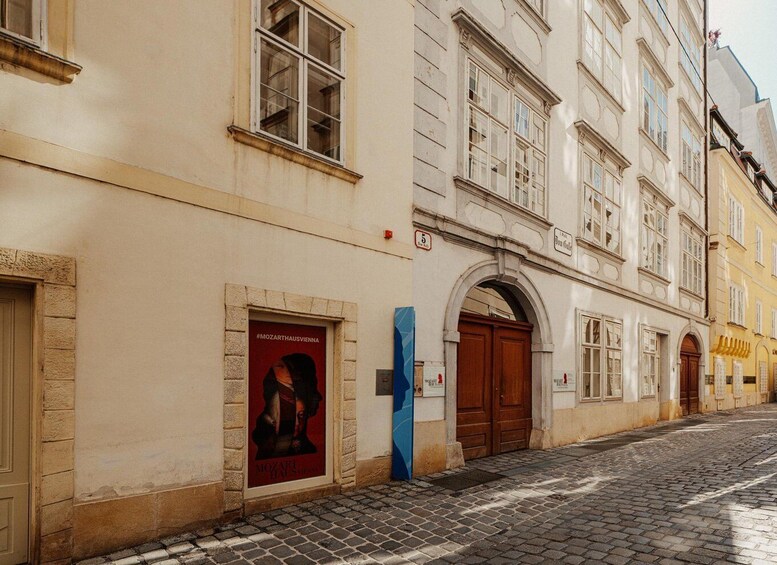 Un edificio histórico con un cartel rojo, una obra de arte azul y una calle adoquinada. 3