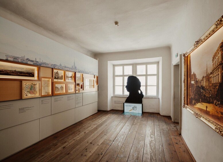 Una galería con obras de arte enmarcadas y una escultura de busto. 2