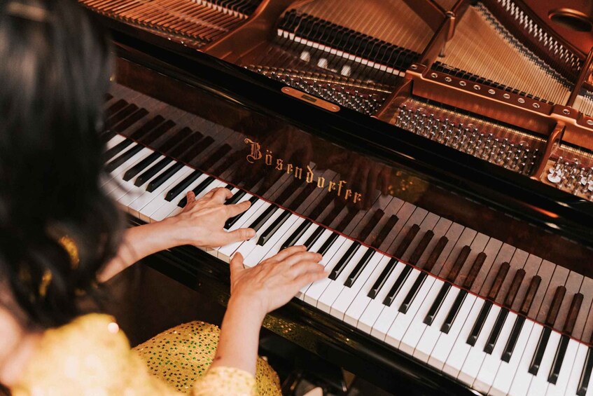 Una persona tocando un piano de cola con una superficie reflectante. 1