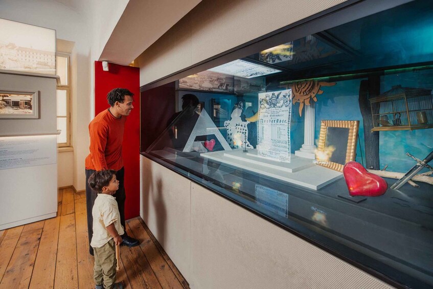 Una exhibición de museo con un vitrina de vidrio que contiene artefactos y una pared roja al fondo. 5