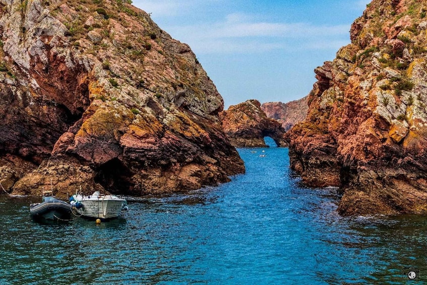 A boat anchored in a narrow waterway between rocky cliffs. 3