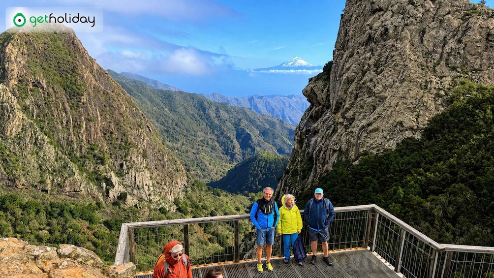 A group of people standing on a metal platform overlooking a mountainous valley. 5