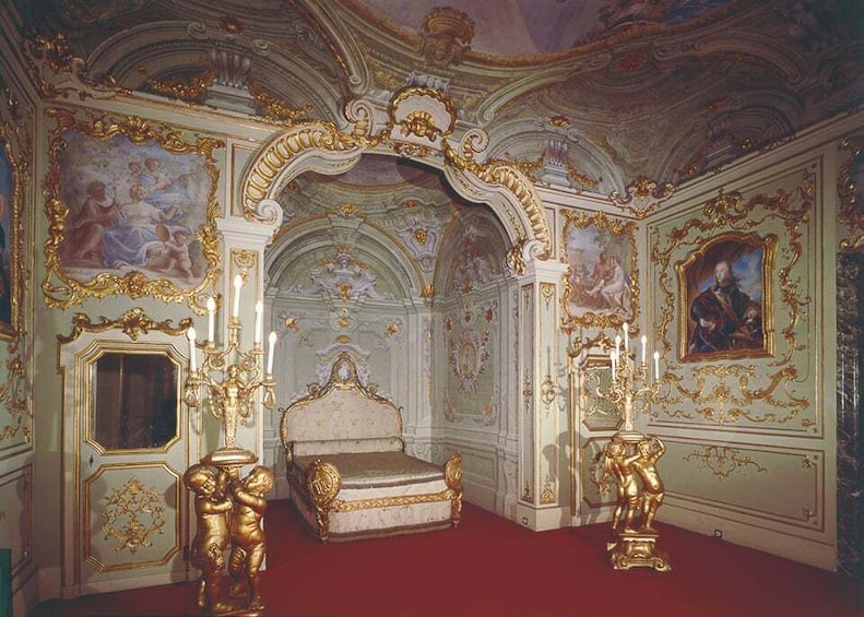 An ornate room with a large bed, gilded furniture, and elaborate wall decorations. 2