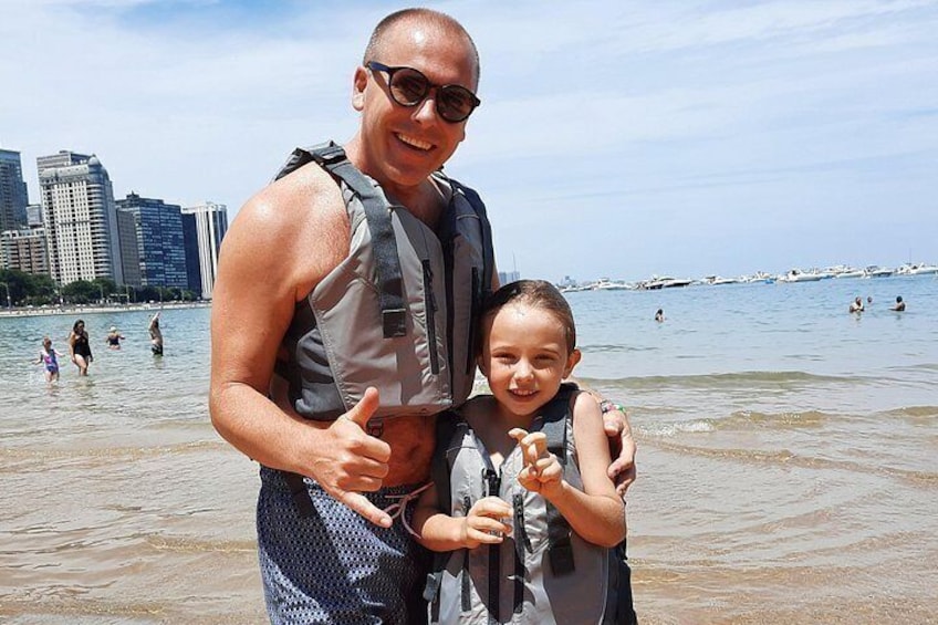 Un uomo e un bambino su una spiaggia, con uno skyline cittadino sullo sfondo. 3