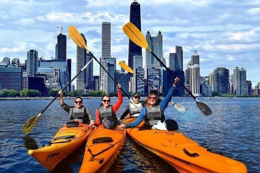 Quattro persone che fanno kayak su un fiume, con uno skyline cittadino sullo sfondo. 5