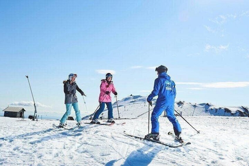 Three skiers on a snowy slope with ski poles, a clear sky, and a small cabin in the background. 2