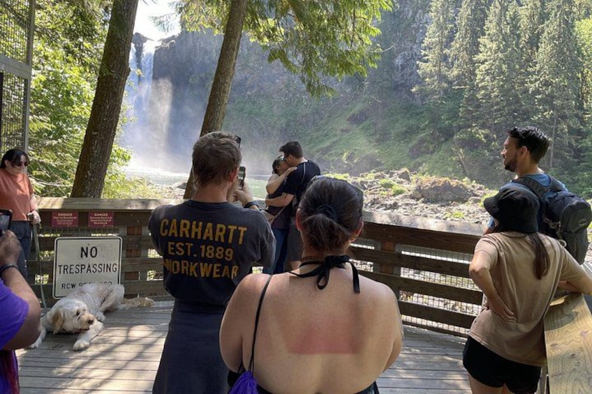 A group of people on a wooden bridge overlooking a waterfall. 2