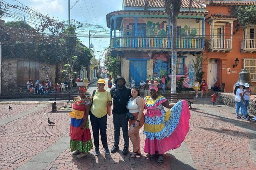 Una calle con edificios coloridos, una fuente y gente con vestimenta tradicional. 1