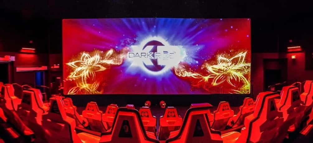 A theater with red seats and a large screen displaying 'DARKSIDE' with a cosmic design. 1