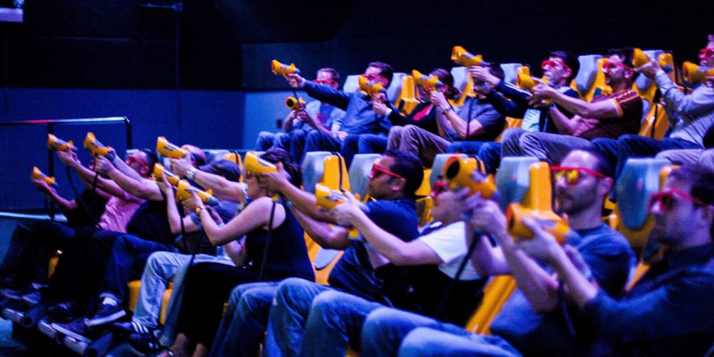People seated in an auditorium holding yellow objects. 2