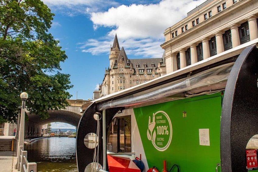 Un bateau électrique vert, entièrement électrique, avec un pont et un château en arrière-plan. 3