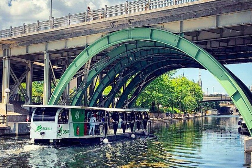 A boat with passengers under a green bridge. 1