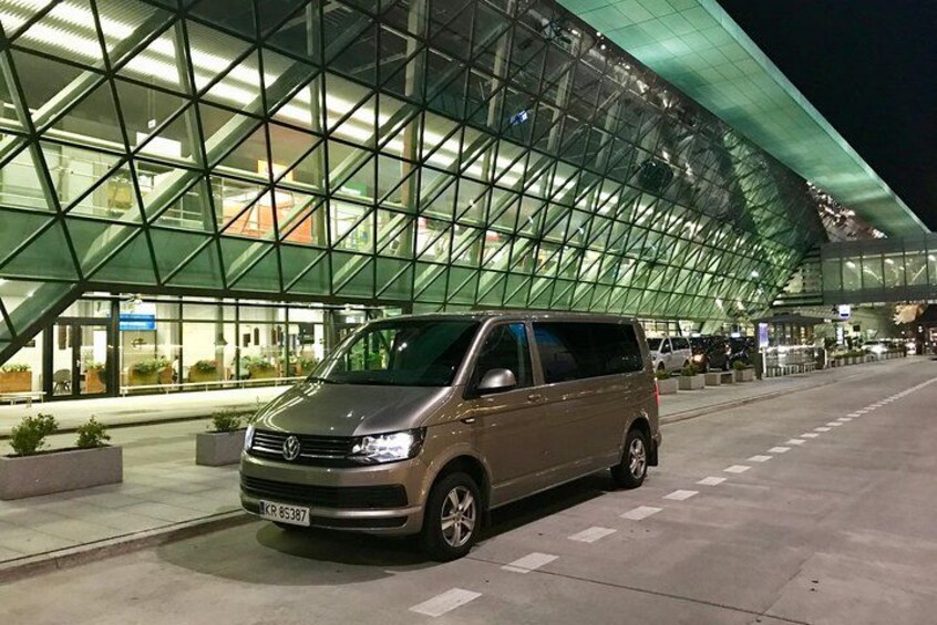 Un fourgon Volkswagen est garé devant un bâtiment moderne à façade vitrée, la nuit. 5