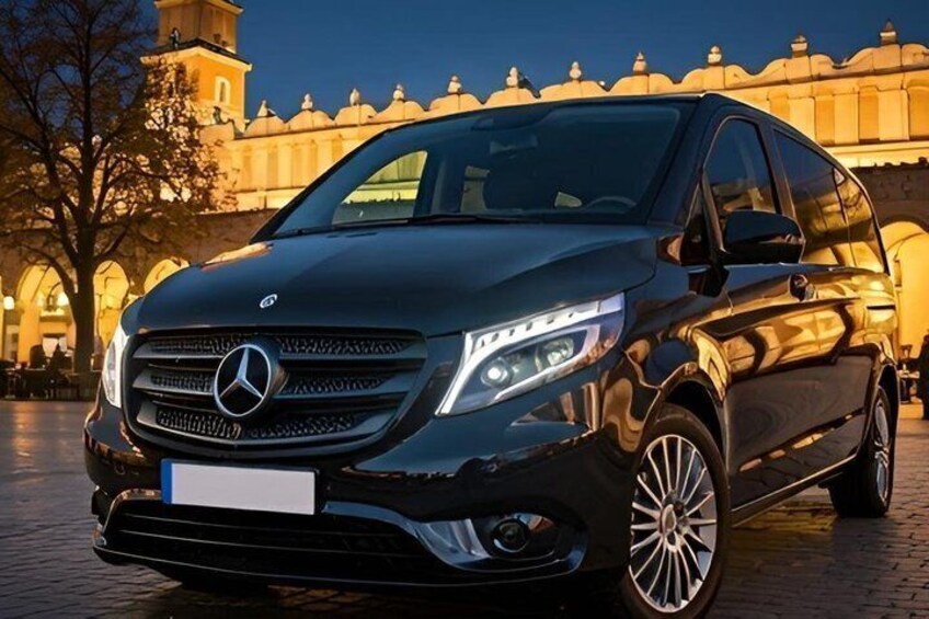 A black Mercedes-Benz SUV parked in front of a historic building with arches and a clock tower. 3
