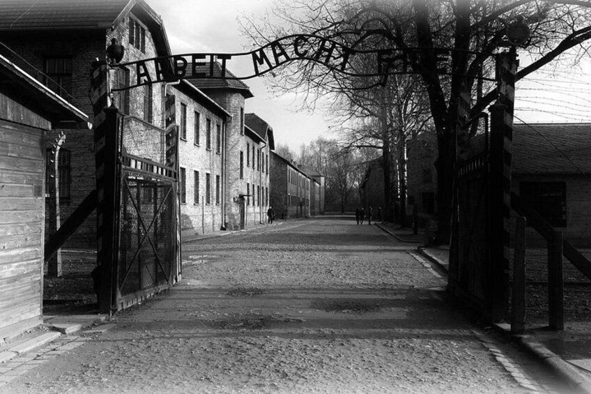 Un edificio histórico con un cartel que dice 'ARBEIT MACHT' y una entrada protegida por una reja. 2