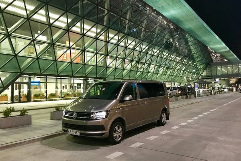 A Volkswagen van parked in front of a modern glass building at night. 4