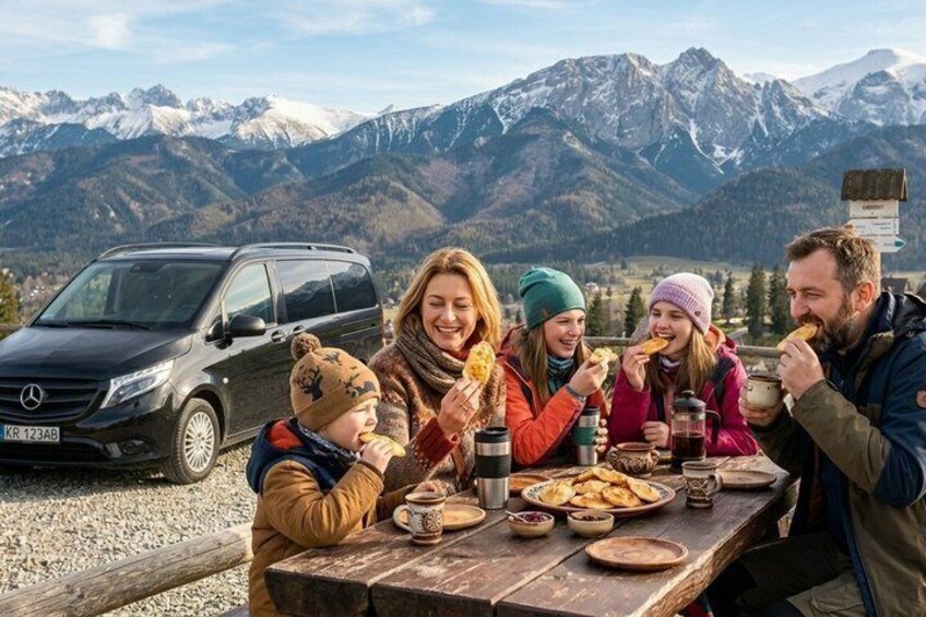 A group of people dining outdoors with a mountain backdrop. 3