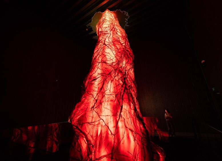 A person in a red, crumpled fabric costume on a stage. 3