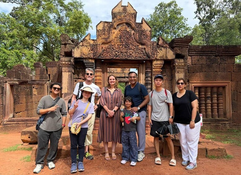 A group of people standing in front of an intricately carved stone structure with a pointed roof. 5