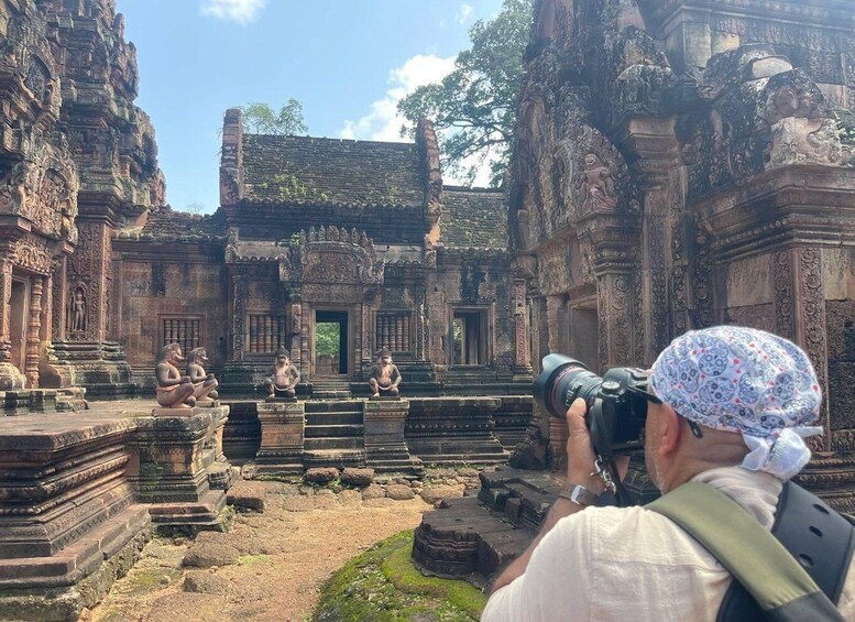 A person taking a photograph of a temple with intricate carvings and statues. 4