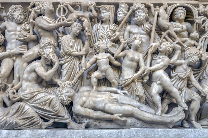 A detailed marble relief sculpture depicting a mythological scene with multiple figures, including gods, humans, and animals, engaged in dynamic interactions. 1