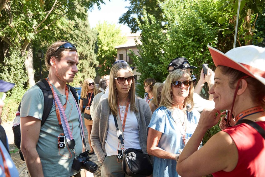 A group of people standing outdoors, some with cameras and wearing lanyards. 3