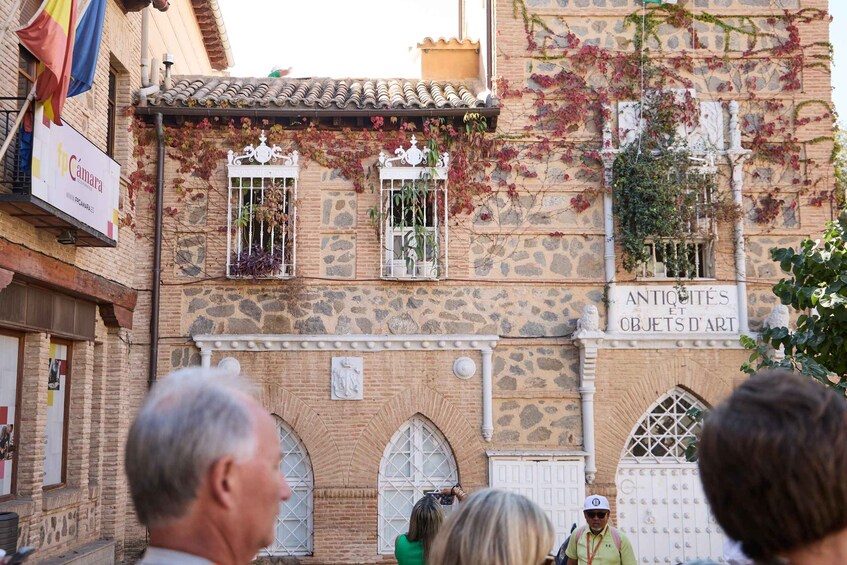 A historic building with stone walls, arched windows, and a sign reading "ANTICHIETES ET OBJETS D'ART". 4