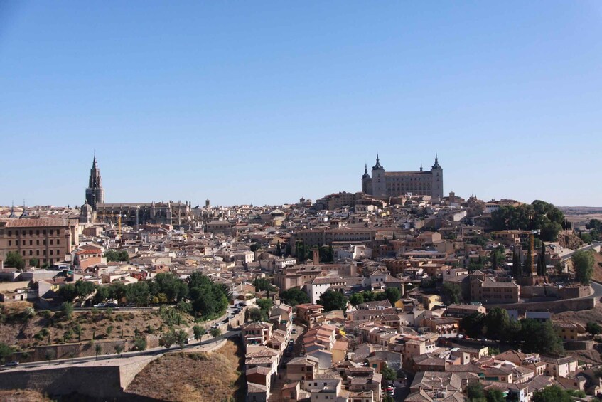 A panoramic view of a historic city with a prominent castle on a hill, a cathedral, and a bridge. 1