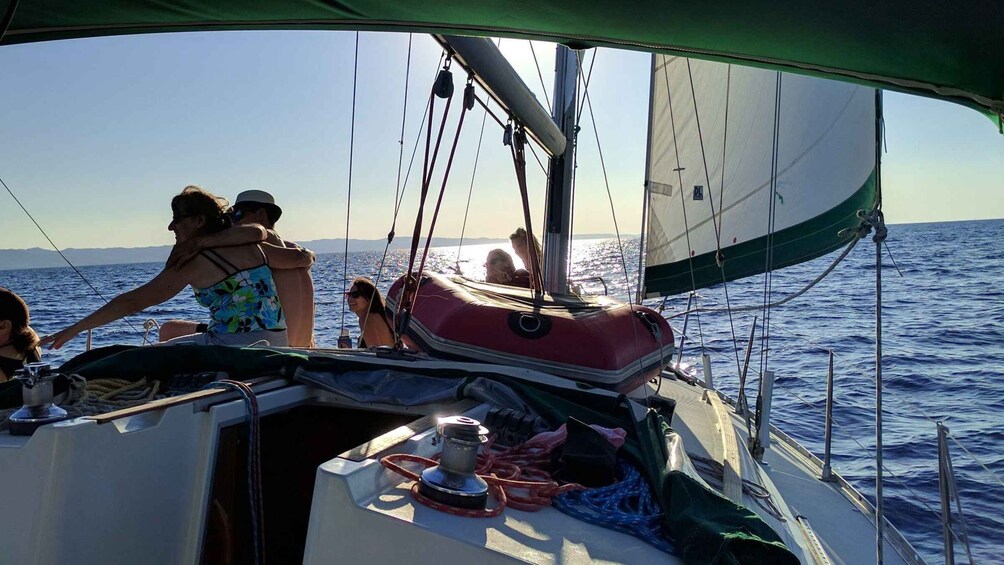 A sailboat with people on deck, a clear sky, and calm waters. 2