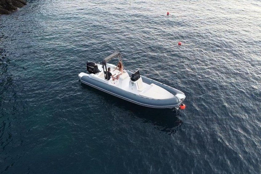 Una pequeña lancha inflable sobre aguas tranquilas, con un motor y dos personas a bordo. 1